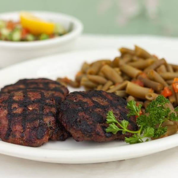 Grilled Israeli kofta patties with green beans and a side salad with lemon.